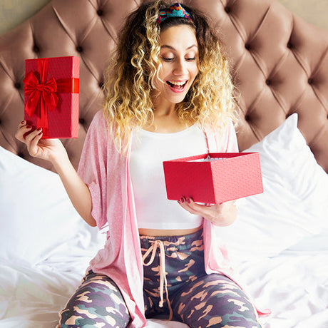 gifts for friends collection, young female sitting on the and holding red gift box